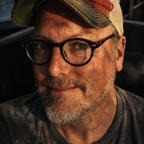 Portrait of Dave Cairns in glasses and a trucker cap
